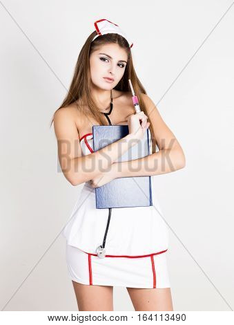 Beautiful smiling sexy nurse holding a syringe and medical history.