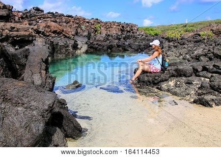 Young woman resting near small lagoon with clear water Genovesa Island in Galapagos National Park Ecuador