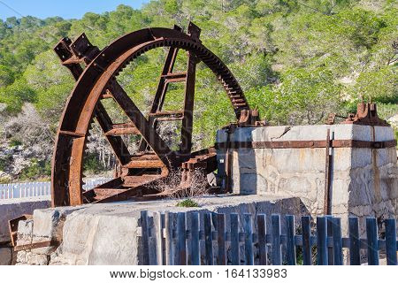 Large rusted and corroded watermill wheel on its stone mount