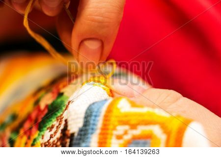 The cross stitching. Photo of woman hands closeup, which holds the needle and the embroidering. Selective focus. 4