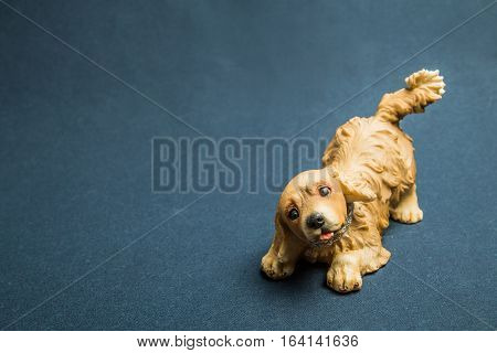 Toy of a dog sat down on forepaws against a dark background