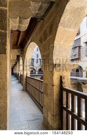 Angled view of one arch with interleaved wooden balustrades at the arcade surrounding the courtyard of caravansary (Wikala) of Bazaraa Medieval Cairo Egypt