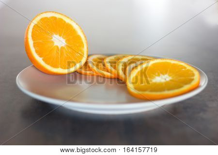 deliciously sweet ripe orange cut into slices served on a plate placed on a light shining bar board