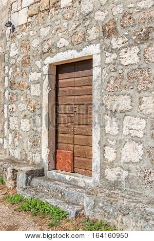 Brown old wooden door of the typical house in Tucepi village, Croatia.