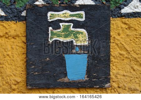 Uniek Wooden  Drinking water sign against a yellow wall