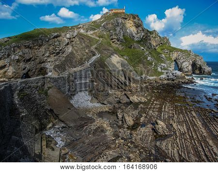 Gastelugache -  island on  coast of  Bay of Biscay belonging to  municipality of Bermeo, Basque Country.  Island is connected to  mainland by  man-made bridge that goes into  winding staircase that spans 237 degrees.