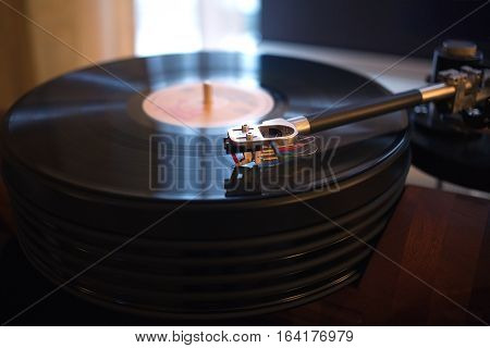 Vintage turntable rotating LP record in a room with subdued light. Horizontal view closeup