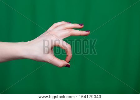 Female Hand shows ok fingers closeup on a green background