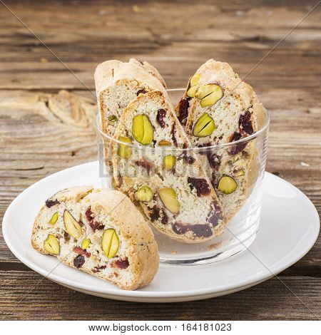 Crispy traditional delicious Italian biscotti cookies or kantuchchi with pistachios and dried cranberries in a glass on a marble background. selective focus