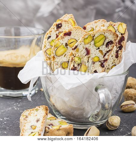 Crispy traditional delicious Italian biscotti cookies or kantuchchi with pistachios and dried cranberries in a glass on a marble background. selective focus