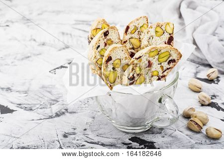 Crispy traditional delicious Italian biscotti cookies or kantuchchi with pistachios and dried cranberries in a glass on a marble background. selective focus