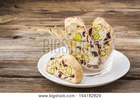 Crispy traditional delicious Italian biscotti cookies or kantuchchi with pistachios and dried cranberries in a glass on a marble background. selective focus