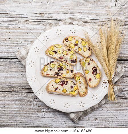 Crispy traditional delicious Italian biscotti cookies or kantuchchi with pistachios and dried cranberries in a glass on wooden background. selective