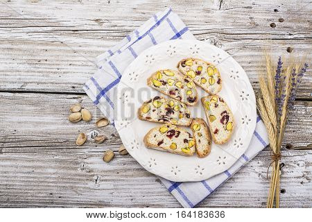 Crispy traditional delicious Italian biscotti cookies or kantuchchi with pistachios and dried cranberries in a glass on wooden background. selective