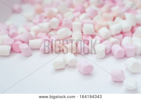 Colorful mini marshmallows background close-up texture. A pile of different mini white pink and orange puffy marshmallows. Marshmallow concept. Wallpaper for desktop. Selective focus.