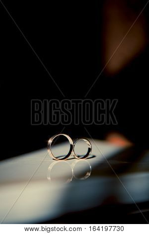 Wedding rings are on the table next to the sun falls