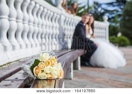 bridal bouquet lying on the bench in front of the bride and groom