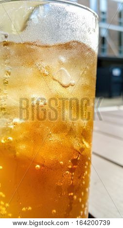 Closeup of a glass of ice cold drink. Subject against a blurred (bokeh) out urban environment with some backlighting.