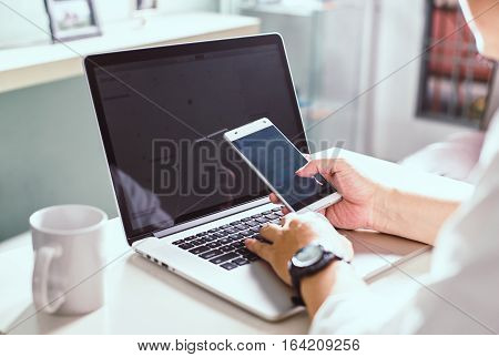 businessman hand using smart phone and keying the data to laptopclose up Seleted focus.