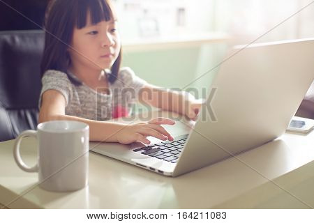 Cute asian little girl using laptop at home . Seleted focus.