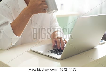 Businessmansitting at the table using his laptop with coffe and headphones. Seleted focus.