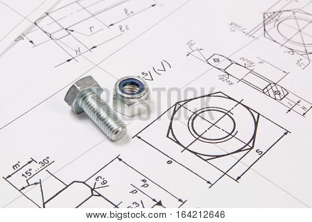 Technical drawings of bolts and nuts. Engineering, technology and metalworking. Metal bolt and nuts on printed drawings background.