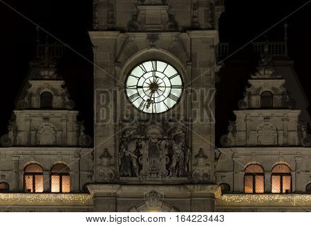 Night view of the illuminated clock on the tower of the town hall