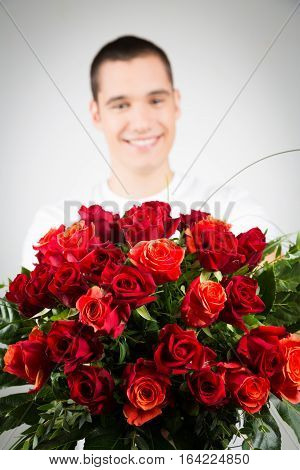 Studio shot of Young man holding bouquet of roses