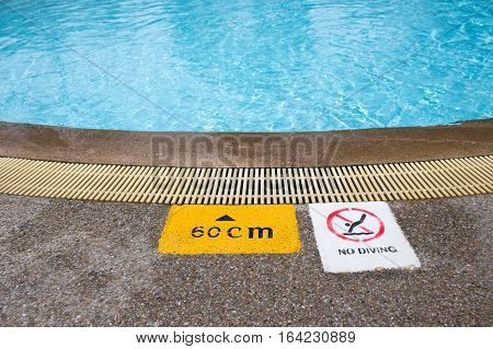 warning and depth sign at clean and clear water swimming pool for children with copy space