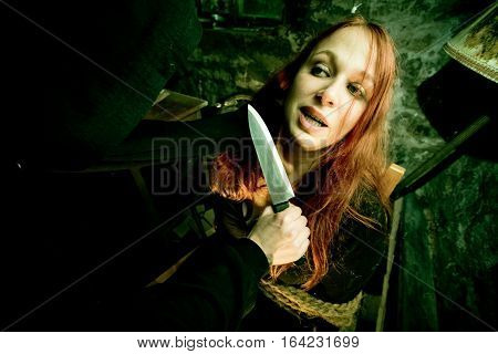 young woman tied to a chair in a dirty cellar