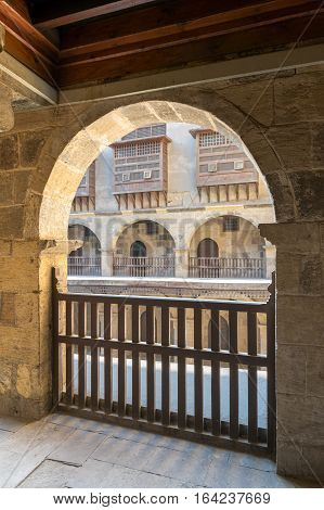 Angled view of one arch with interleaved wooden balustrades at the arcade surrounding the courtyard of caravansary (Wikala) of Bazaraa Medieval Cairo Egypt
