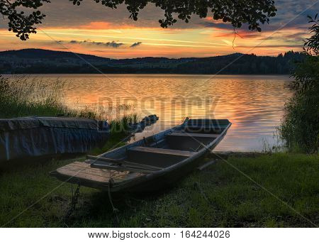 Rowboat on beautiful lake with dramatic sunset.The morning of the loch.Landscape with boat.A fishing boat tied at the shore of a Lipno lake Czech Republic.Nature landscape.