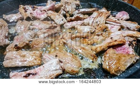 Strips of fillet steak being fried on a ceramic hotplate. Some white smoke can be seen sizzling up to give the image a slight haze.