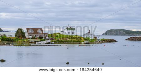 Small village community, Twillingate, Newfoundland.  Homes along shoreline.  Boats & dories at docks in a small cove.  Woodpile bears witness to coming cold.  Hardy community along the Island's edges.