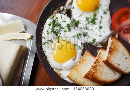 Delicious fried eggs for breakfast on a wooden table with grilled bread