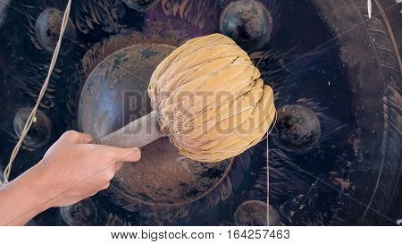 Hand of Asian young man hit big gong or Thai instrument in temple for pray. Thai instrument concept.