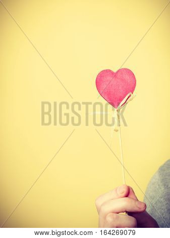 Symbolism romance relationship affection valentines concept. Male person holding heart on stick. Someone presenting love symbol on pole.