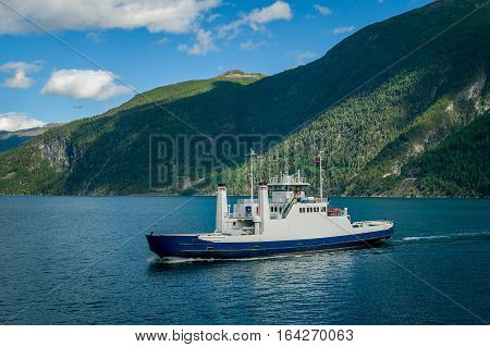 Small transportation boat in the fjord of Norway. Close view from one ferry deck to another. Mountain background.