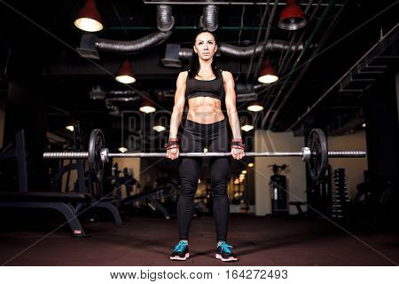 Muscular young fitness woman doing heavy deadlift exercise in gym