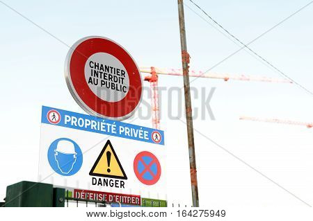 Chantier interdit au publique translated as Construction site forbidden for public from French language with cranes in the background