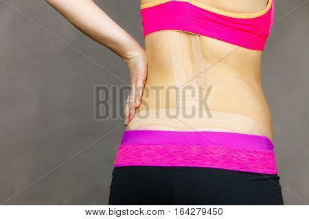 Woman with kinesiotaping application for back pain. Backache alternative kinesio tape therapy method. Health and body care.