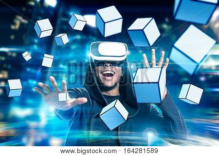Portrait of an excited African American man in virtual reality glasses playing a game with floating cubes. Toned image. Double exposure