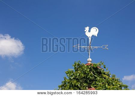 White rooster weather vane show the wind direction on blue sky background