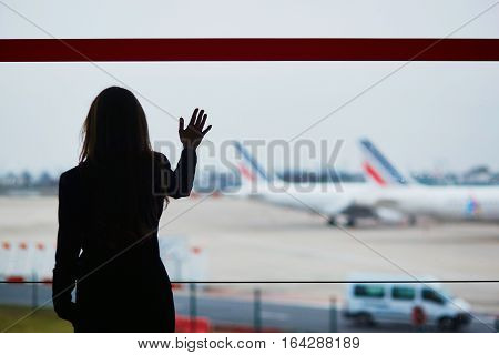 Woman With Hand Luggage In International Airport, Looking Through The Window At Planes