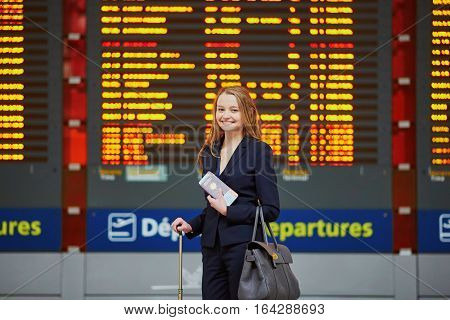 Woman With Hand Luggage In International Airport Terminal, Looking At Information Board