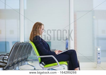 Woman In International Airport Terminal, Working On Her Laptop