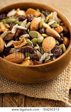 Dried fruit and nuts trail mix with almonds, raisins, seeds and apples in a wooden bowl