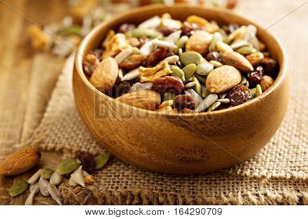 Dried fruit and nuts trail mix with almonds, raisins, seeds and apples in a wooden bowl