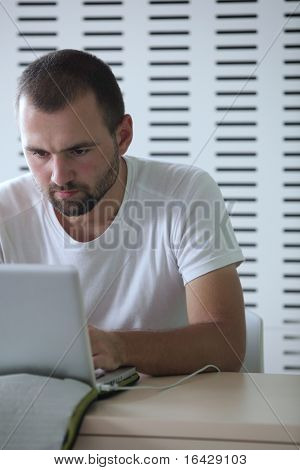 Junge männliche College-Studenten, die Arbeiten auf seinem Laptopcomputer in einem Klassenzimmer