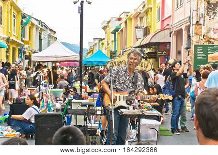 PHUKET THAILAND SEPTEMBER 27: Street artist musician entertains tourists at the walking street among old building Chino Portuguese style on street of Phuket town Thailand on September 27 2016.